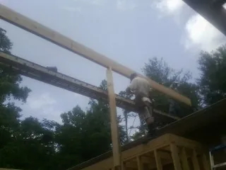 Carpenter setting a ridge beam over a new addition frame — Ice Dam Removal by Roofing Brothers in Cutler