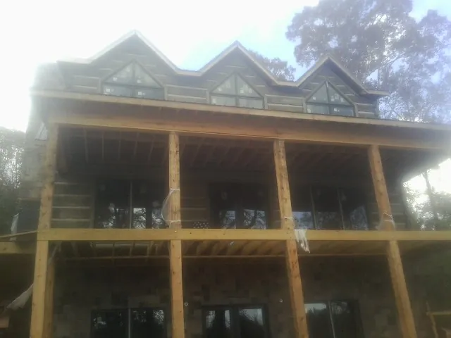 Dormers and porch framing on a large log home under construction — Roof Coating work by our crew in Cutler