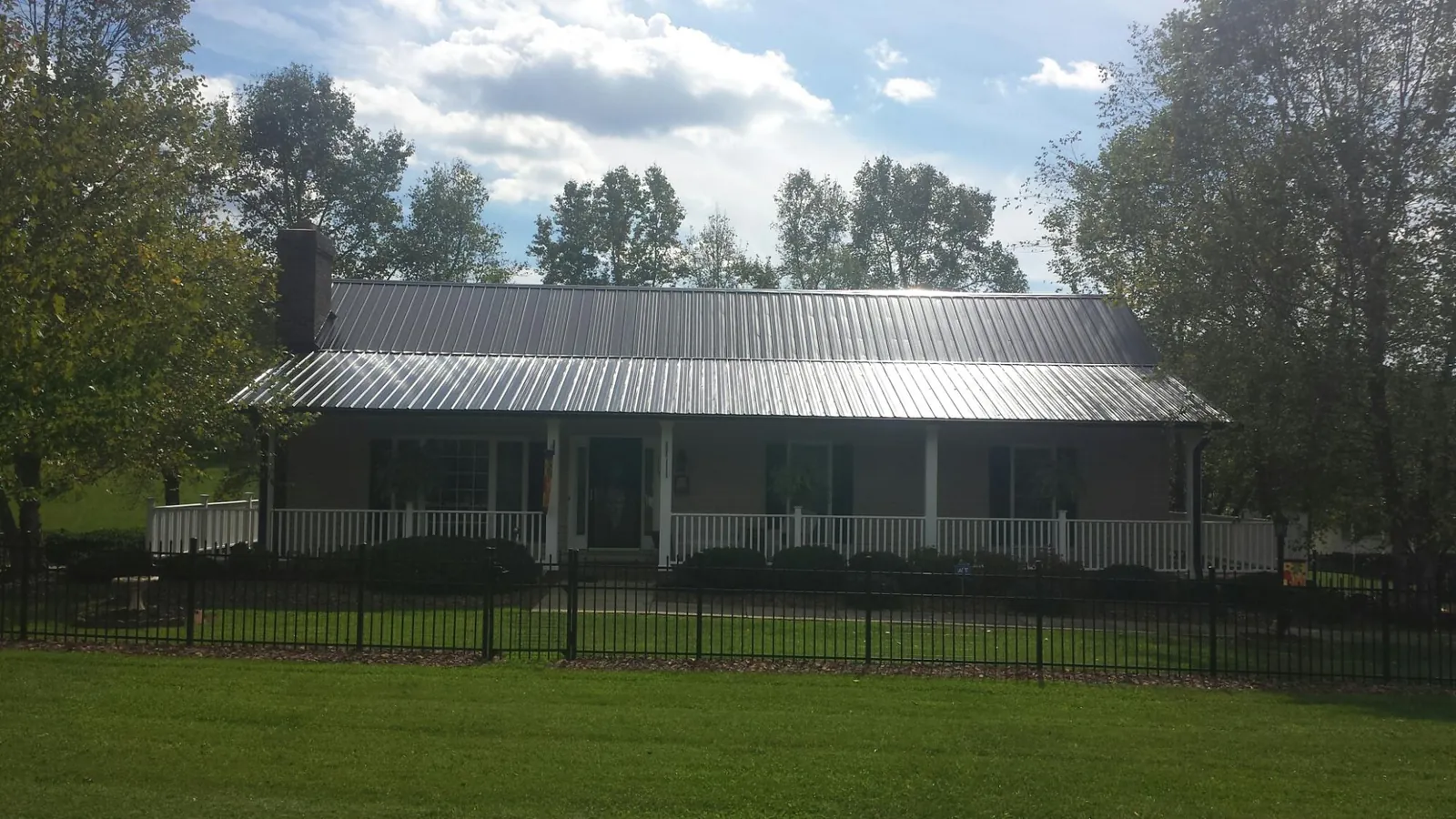 Gray metal roof on a brick ranch with a full width front porch — Gutter Guard Installation work by our crew in Cutler