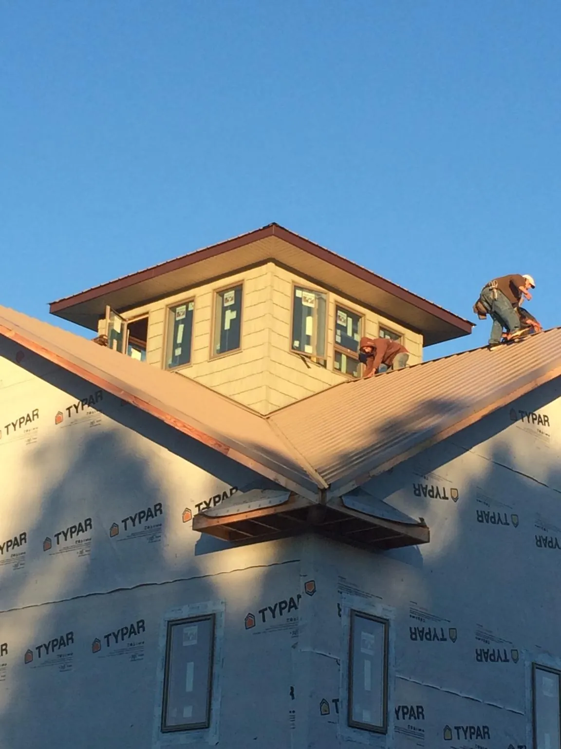 Roofers working around a rooftop cupola on a new metal roof at sunset — Roof Waterproofing in Cutler by Roofing Brothers